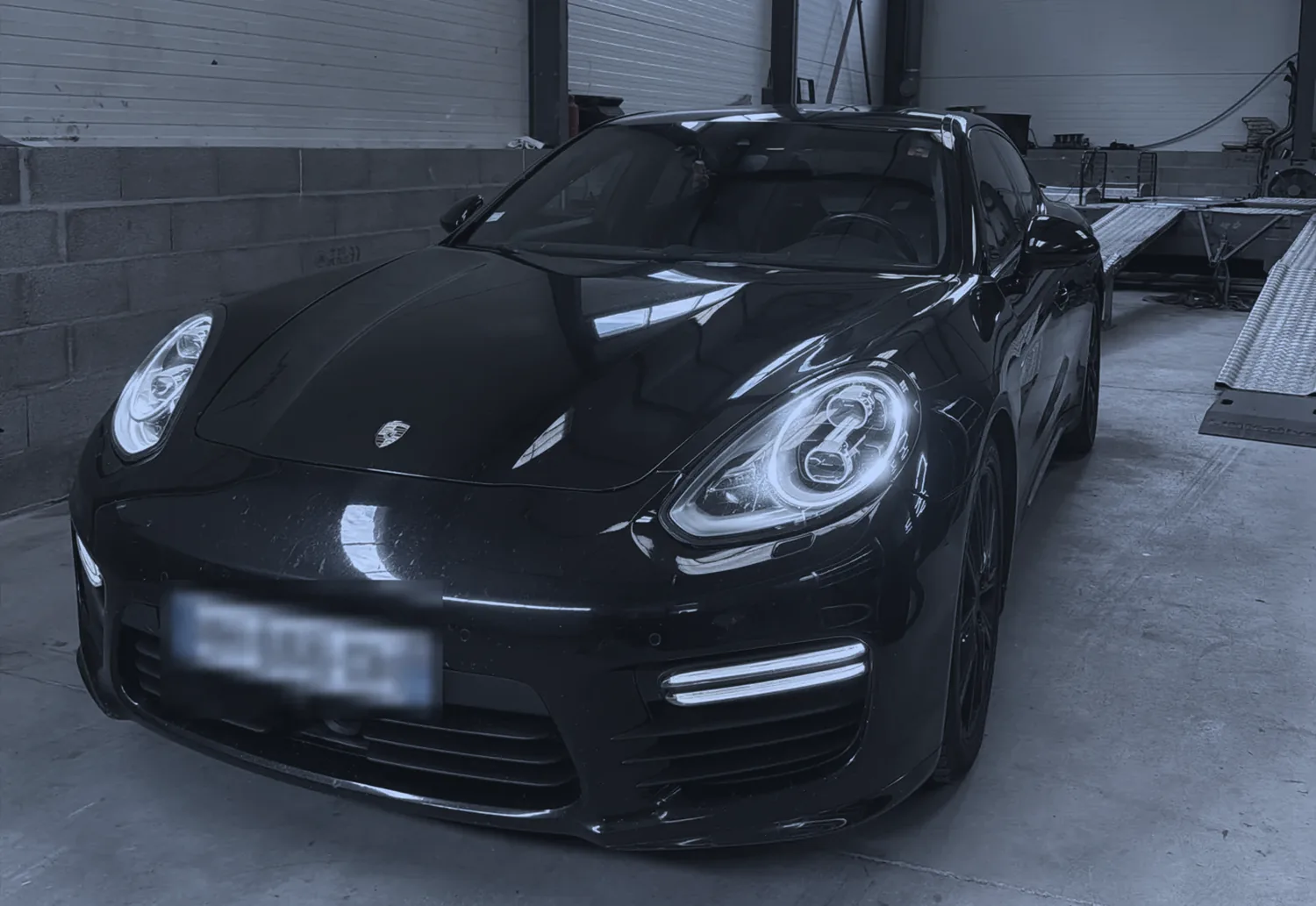 Une Porsche Panamera, phares allumés, dans l'atelier TLG